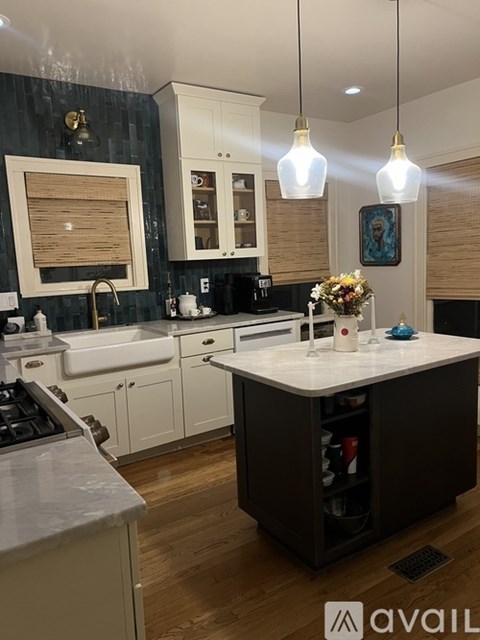 A modern kitchen with a large island and pendant lights.