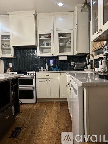 A kitchen with white cabinets and a wooden floor.