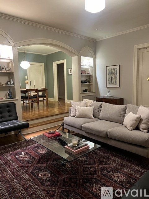 A living room with a grey couch and a red rug.