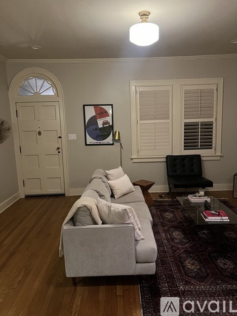 A living room with a grey couch and a rug.