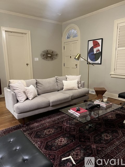 A living room with a grey couch, a glass coffee table, and a rug.