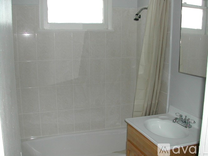A bathroom with a white sink and a white tiled shower.