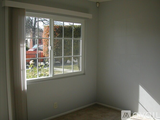 A room with a window showing a red car and trees outside.