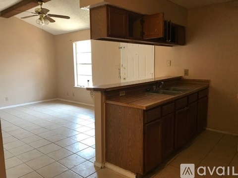 A kitchen area with a counter, cabinets, and a fan.