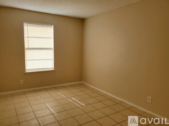 A room with beige walls and a window with blinds.