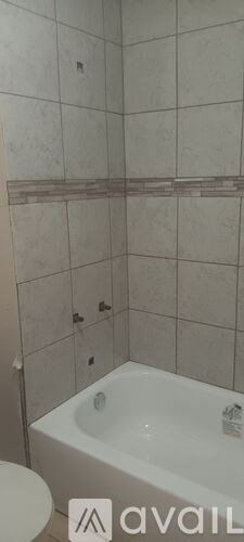 A bathroom with a white tub and tiled walls.