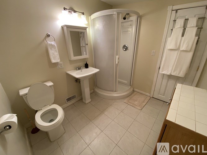 A bathroom with a toilet, sink, mirror, and shower.