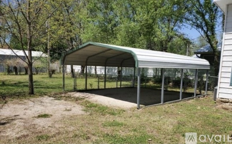 A green and white metal carport is in a yard.