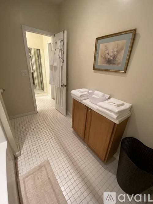 A bathroom with a toilet, sink, and a painting on the wall.