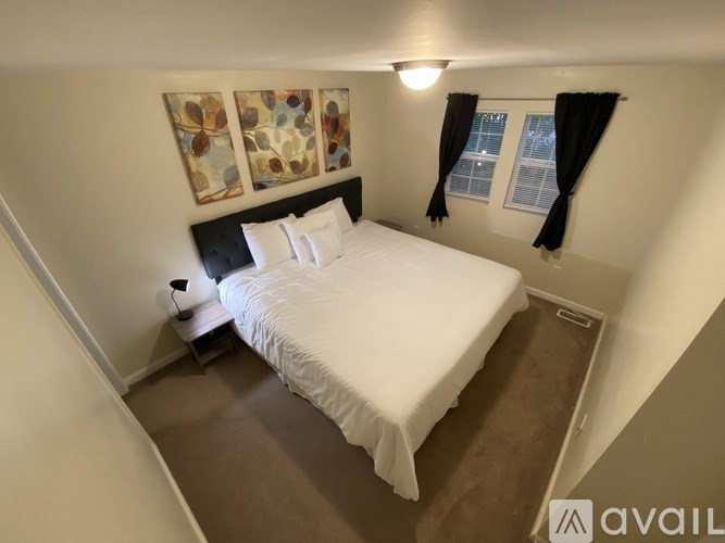A bedroom with a white bed and a painting on the wall.