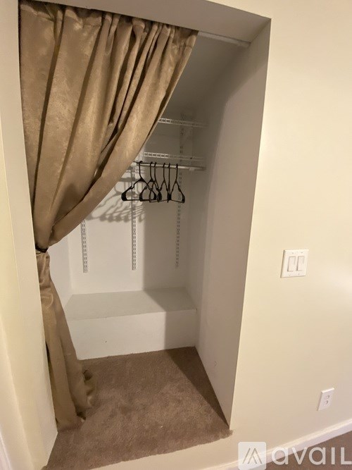 A beige curtain is hanging in front of a white closet.