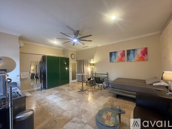 A bedroom with a bed, chair, and a fan.