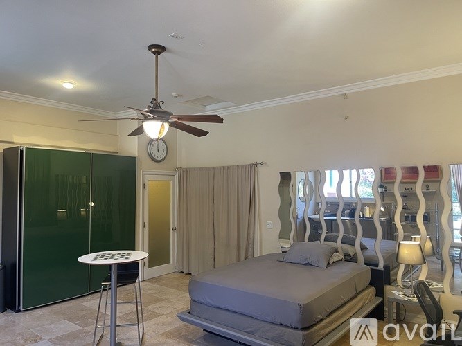A bedroom with a bed, a table, and a ceiling fan.