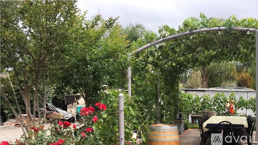 A garden with a wooden barrel and a table with chairs.