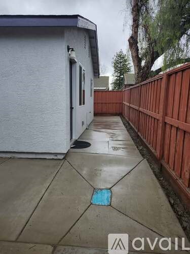 A wet concrete sidewalk with a blue square painted on it.