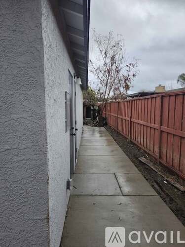 A narrow alley with a metal fence on one side and a building on the other.
