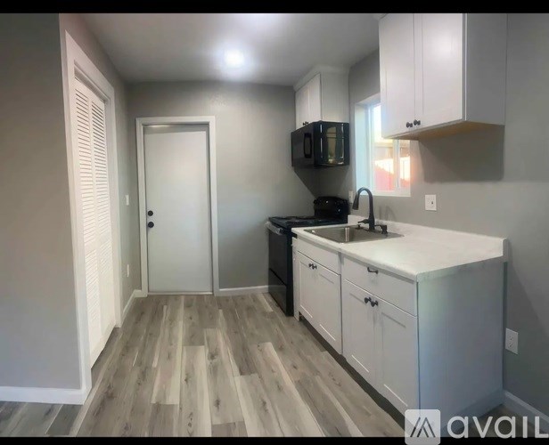 A kitchen with a white countertop and wooden flooring.