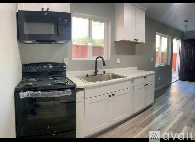 A kitchen with a black stove top oven and white cabinets.