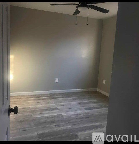 A room with a ceiling fan and wooden flooring.