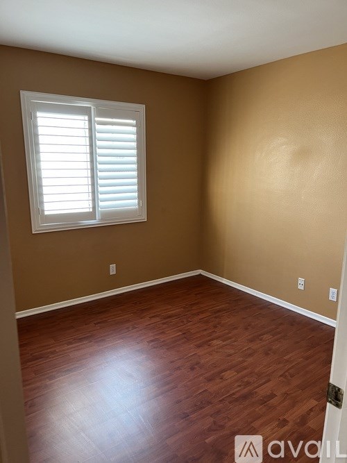 A room with wooden floors and a window with white blinds.