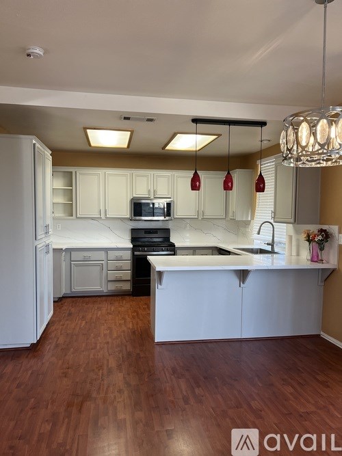 A kitchen with white cabinets and a wooden floor.