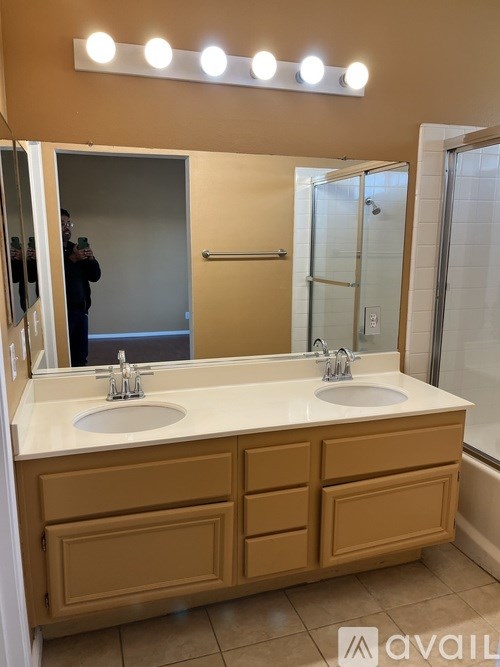 A bathroom with a double sink vanity and lights above it.