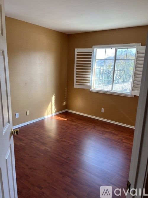 A room with wooden floors and a window with shutters.