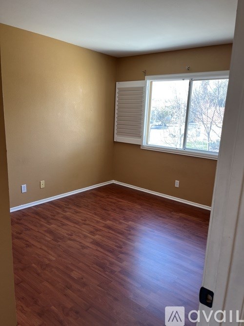 A room with wooden flooring and a window with blinds.