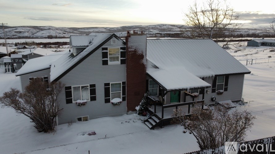 A house with a grey roof and a red door is surrounded by snow.