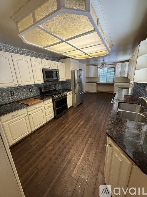 A kitchen with wooden floors and white cabinets.