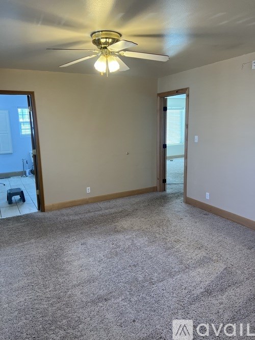 A room with a ceiling fan and carpeted floor.