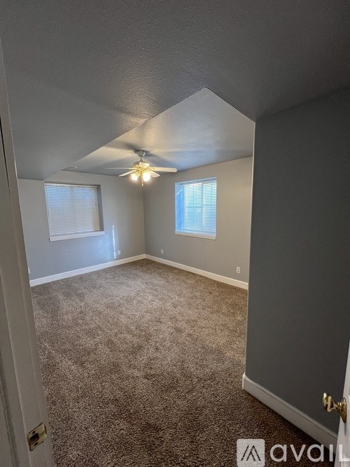 A room with a carpeted floor and a ceiling fan.
