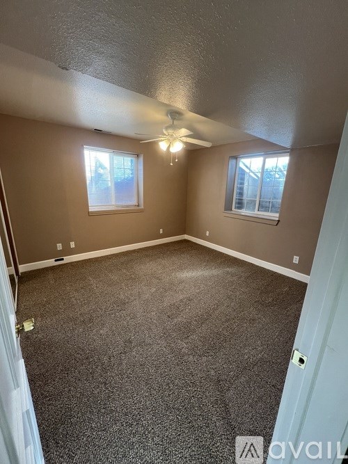A room with a carpeted floor and a ceiling fan.