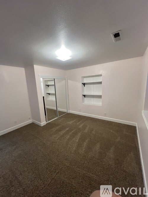A carpeted room with a door and a window.