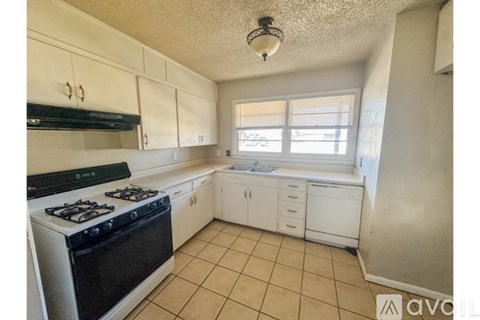 A kitchen with a black stove top oven and white cabinets.