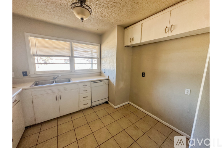 A kitchen with white cabinets and a sink under a window.