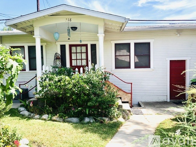 A white house with a red door and windows.