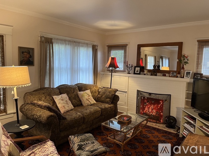 A living room with a brown couch, a fireplace, and a television.