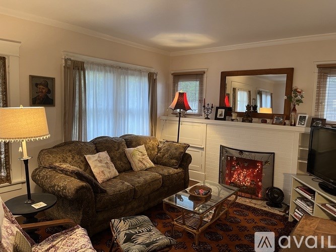 A living room with a brown couch, a fireplace, and a television.