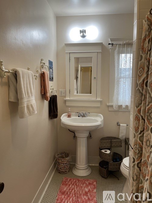 A bathroom with a white pedestal sink and a mirror above it.