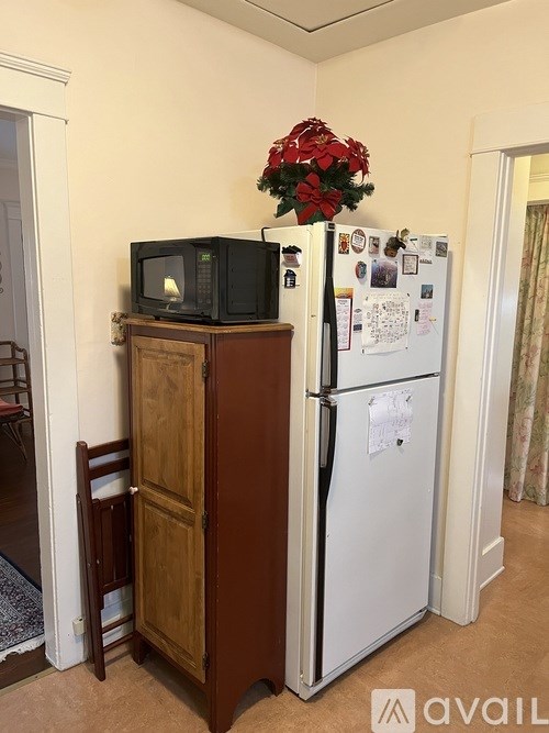 A kitchen with a white fridge and a microwave on top of a cabinet.