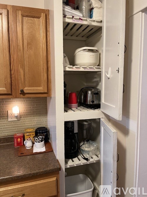A kitchen cabinet is open, revealing a messy interior with various items.