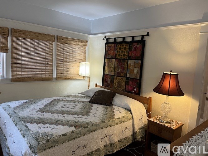 A bedroom with a bed, nightstand, and window with blinds.