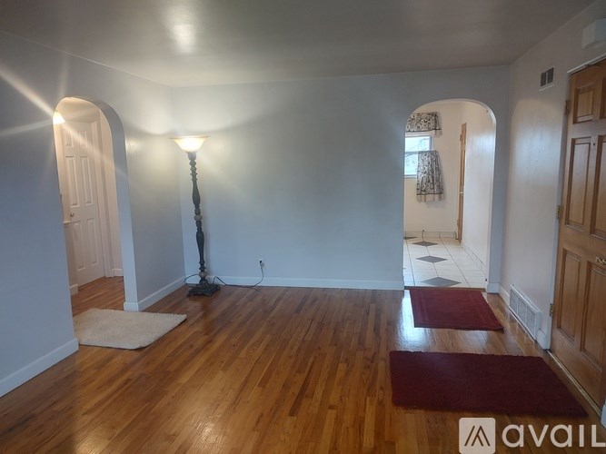A room with wooden floors and a red rug in the foreground.