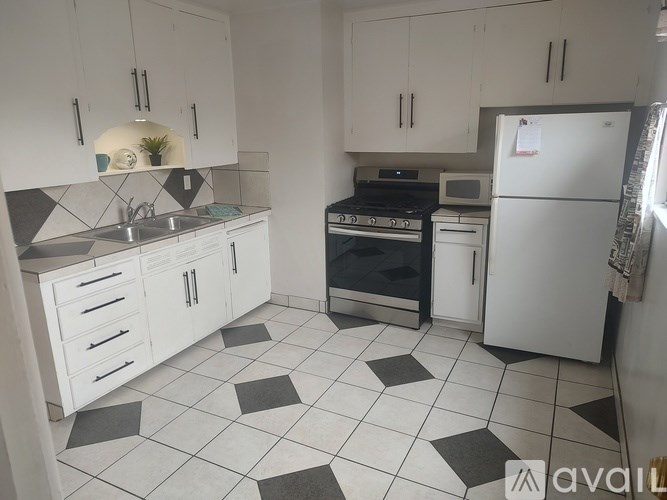 A kitchen with white cabinets and black and white tiled flooring.