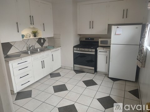A kitchen with white cabinets and black and white tiled flooring.