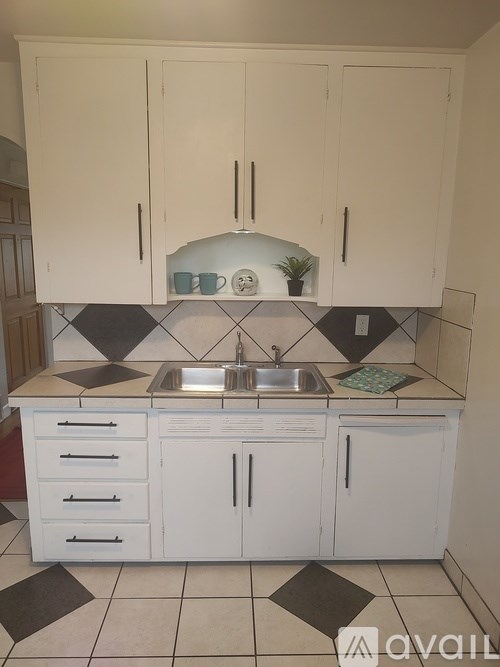 A kitchen with white cabinets and a black and white checkered floor.