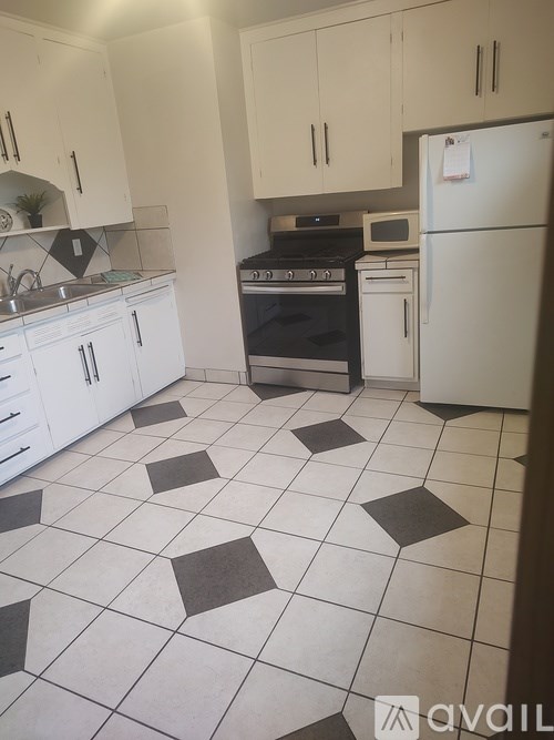A kitchen with white cabinets and a black and white floor.