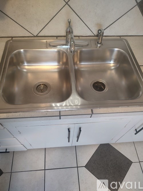 A double sink in a kitchen with a white cabinet below it.