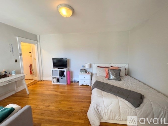 A bedroom with a bed, a desk, and a television.